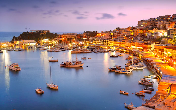 Athens Riviera harbor at sunset with boats and illuminated waterfront.