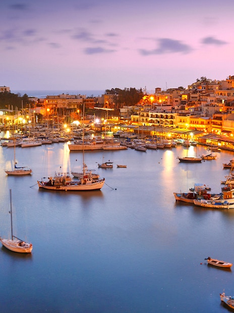 Athens Riviera harbor at sunset with boats and illuminated waterfront.