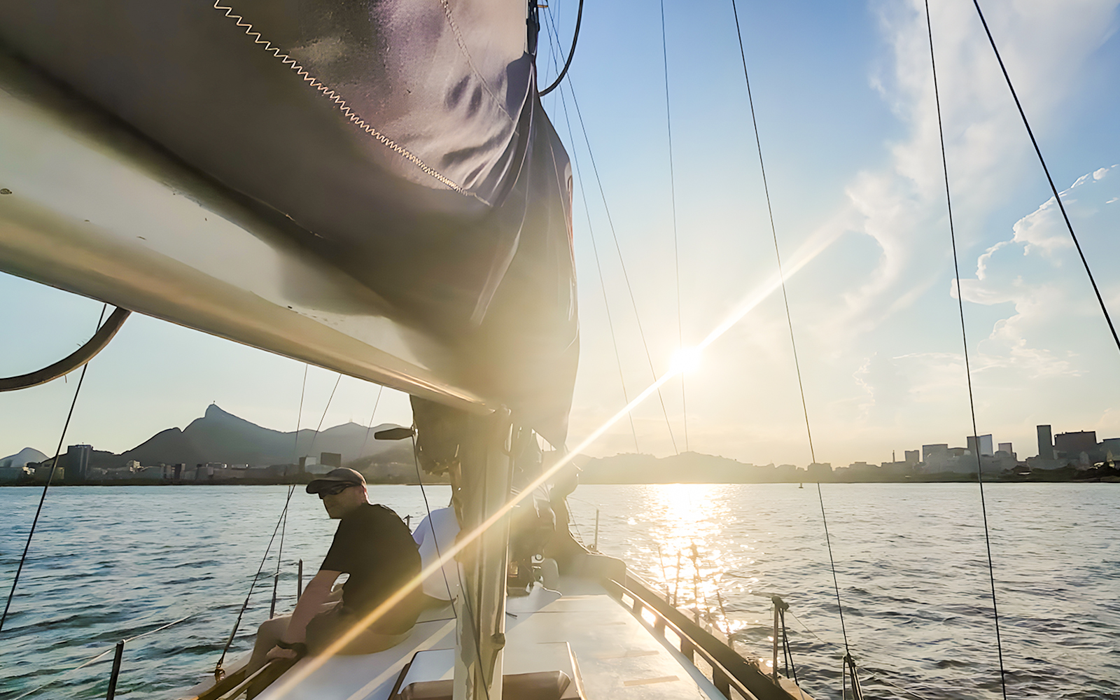 Tourist on sailboat viewing Rio de Janeiro skyline at sunset.