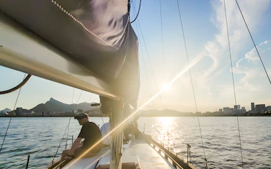 Tourist on sailboat viewing Rio de Janeiro skyline at sunset.