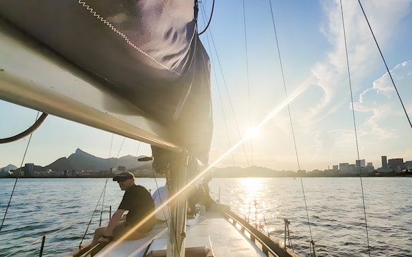 Tourist on sailboat viewing Rio de Janeiro skyline at sunset.