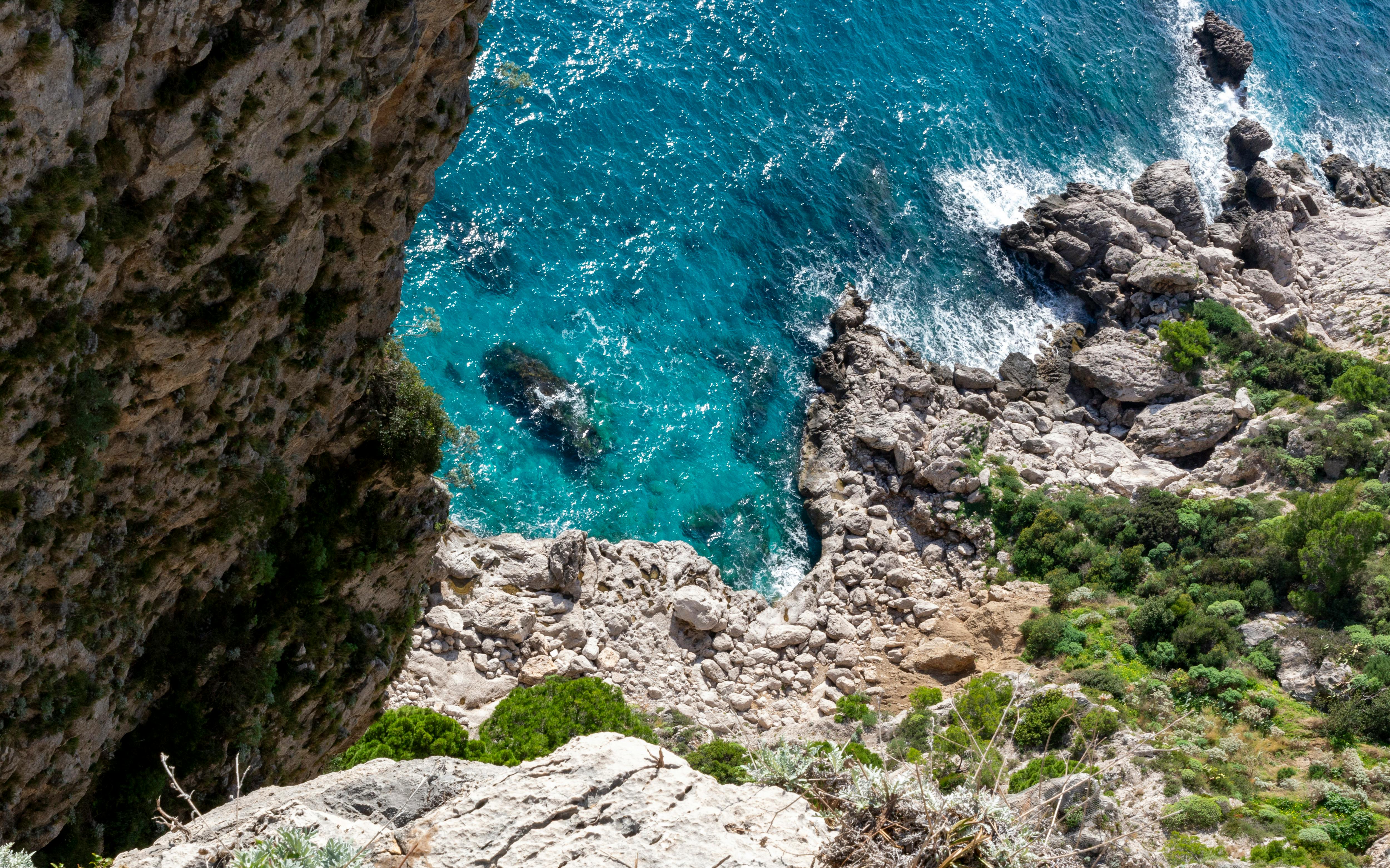 Top down view of rocky coastline and turquoise sea at Capri Island.