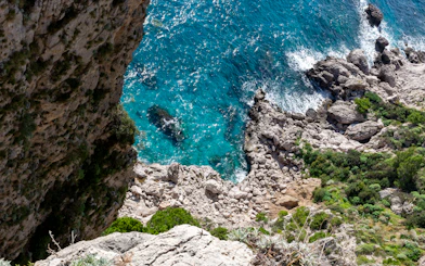 Top down view of rocky coastline and turquoise sea at Capri Island.