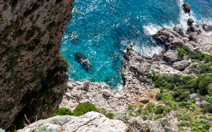 Top down view of rocky coastline and turquoise sea at Capri Island.