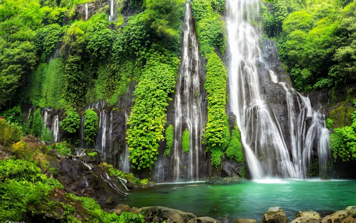 Banyumala Twin Waterfalls cascading over lush green cliffs into a turquoise pool in Bali.