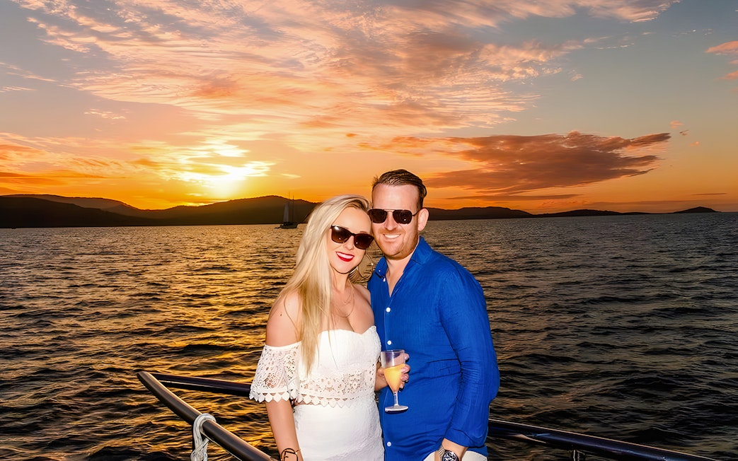 Couple enjoying a sundowner cruise at sunset, Airlie Beach.