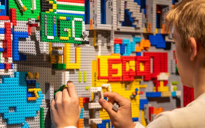 Person assembling colorful LEGO bricks at The Art of the Brick Immersive Experience in Australia.