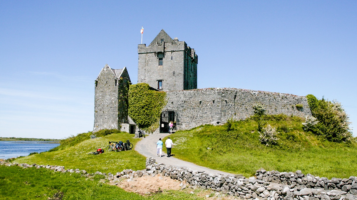 Dunguaire Castle in Ireland with visitors walking towards the entrance.
