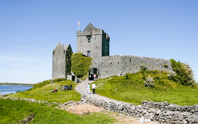 Dunguaire Castle in Ireland with visitors walking towards the entrance.