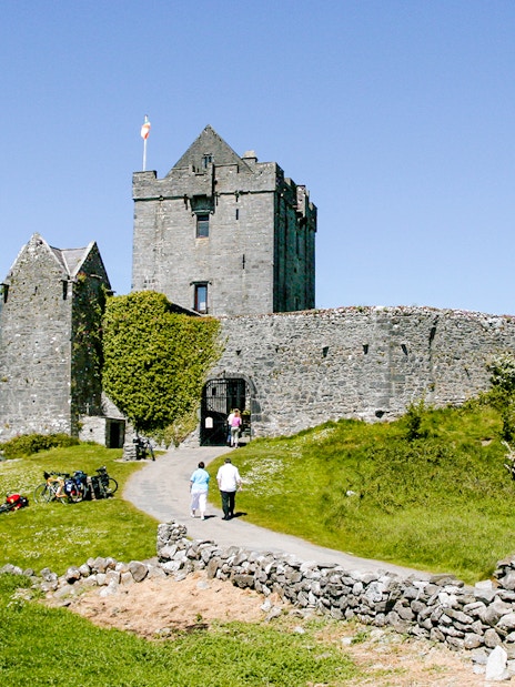 Dunguaire Castle in Ireland with visitors walking towards the entrance.