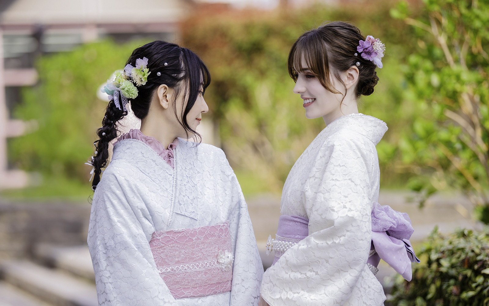 Tourists in traditional Yukata smiling at each other in a garden setting.