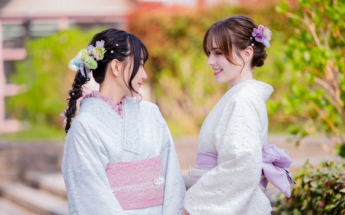 Tourists in traditional Yukata smiling at each other in a garden setting.