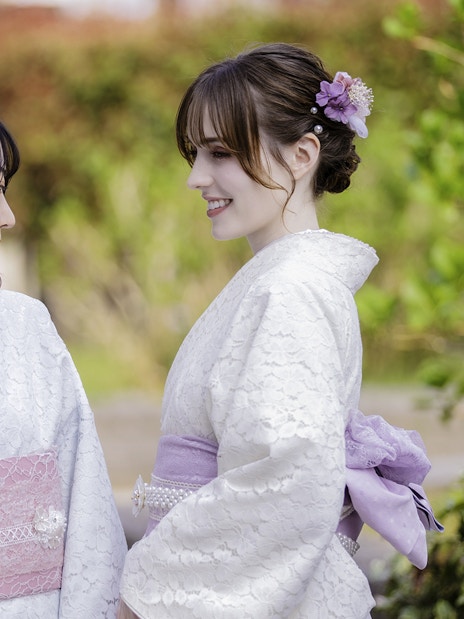 Tourists in traditional Yukata smiling at each other in a garden setting.