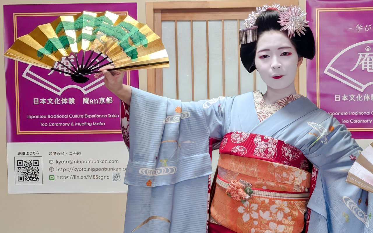 Maiko in traditional attire holding a Japanese fan in Kyoto.