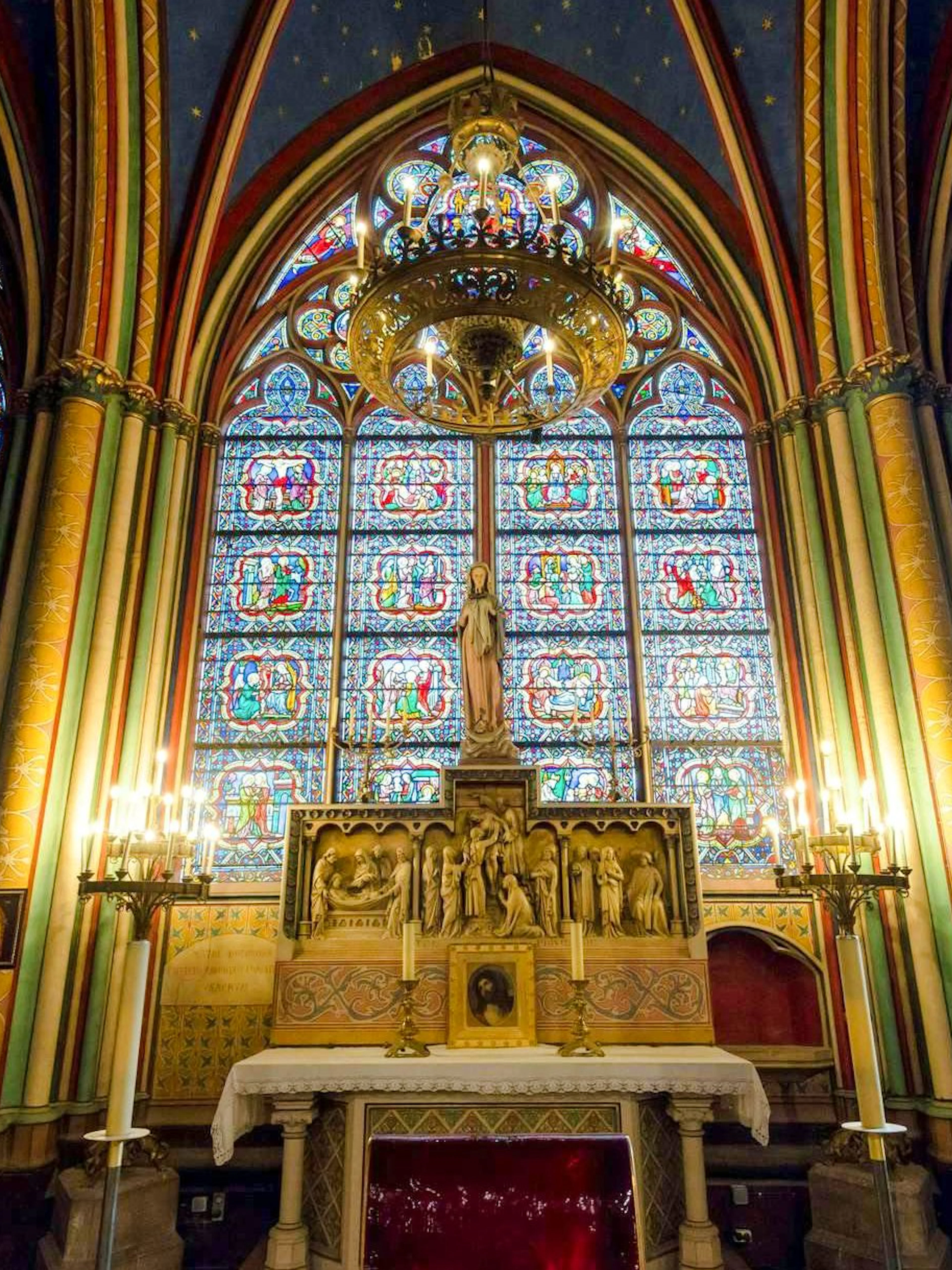 Notre-Dame treasury stained glass windows and altar statues in Paris.