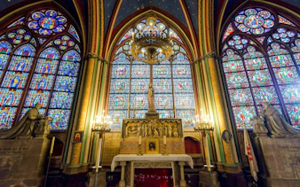 Notre-Dame treasury stained glass windows and altar statues in Paris.