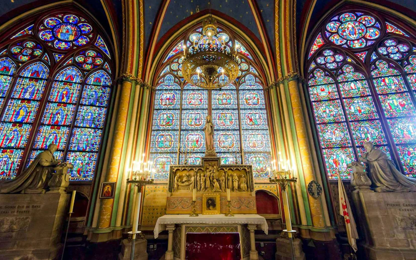 Notre-Dame treasury stained glass windows and altar statues in Paris.