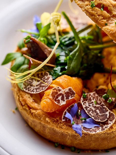 Gourmet dish with truffle slices and greens at At.Mosphere, Burj Khalifa.