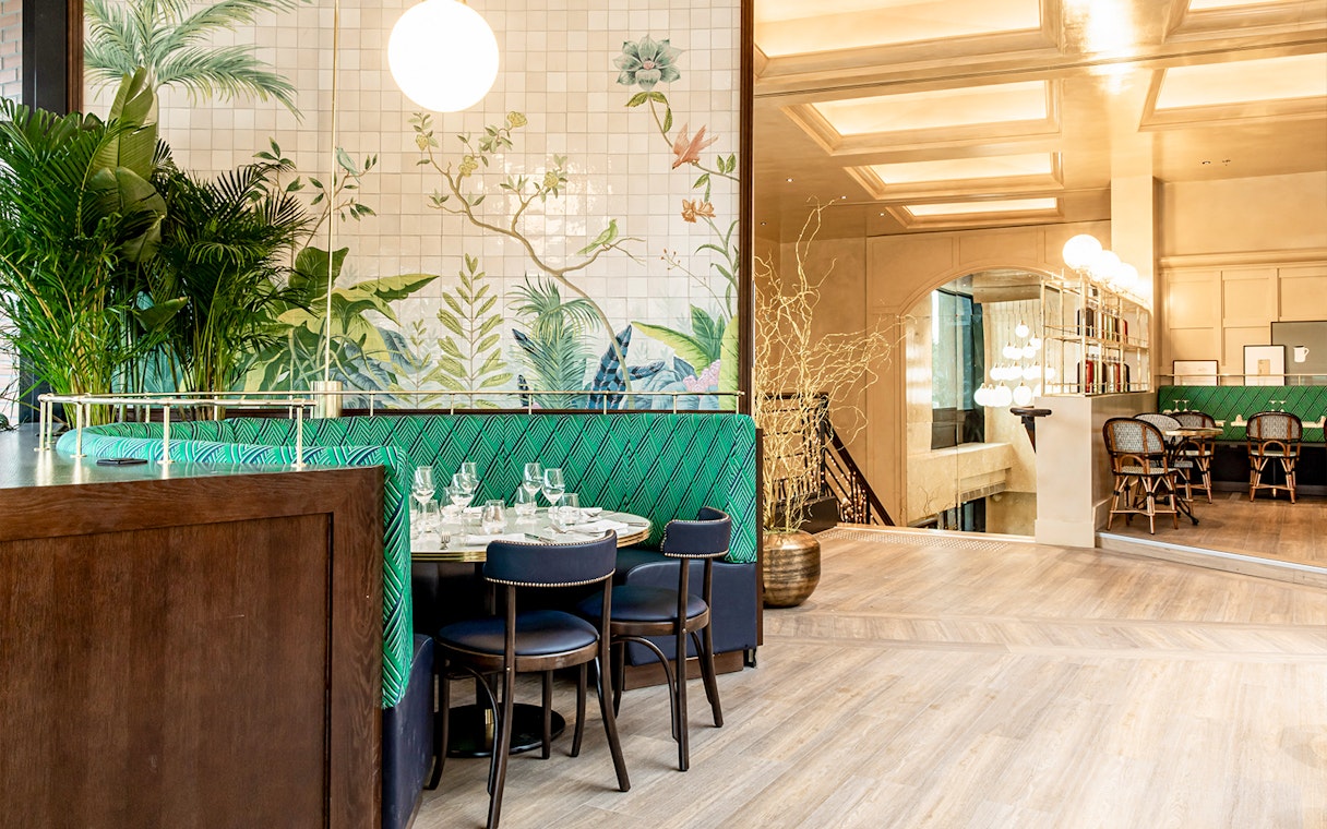 Dining area with green seating and botanical wall art at Flottille's snack & go.