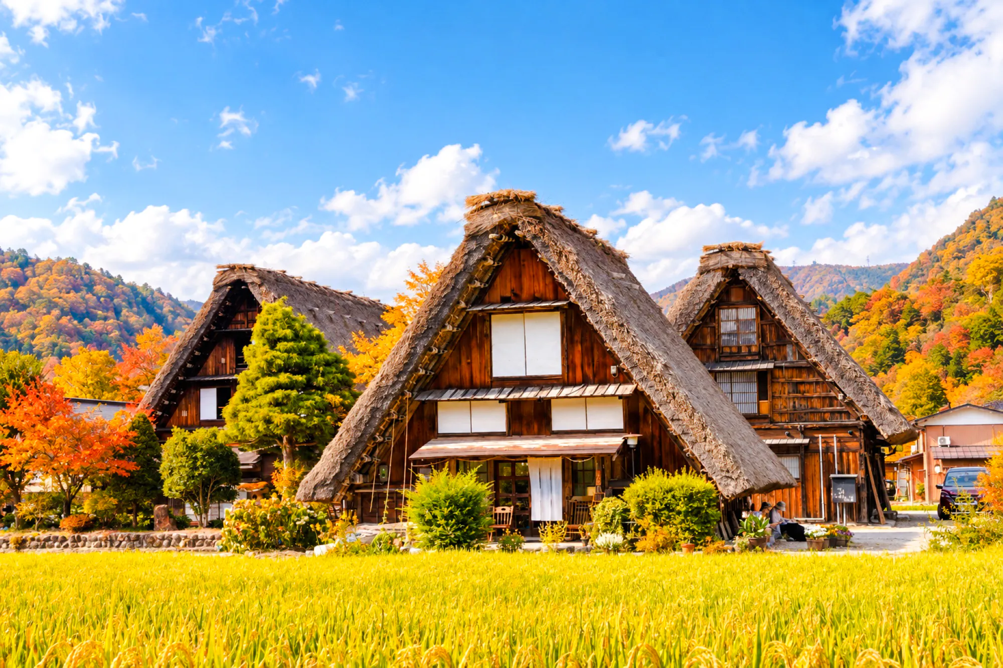 Traditional gassho-style houses in Shirakawa-go village, surrounded by autumn foliage.