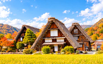 Traditional gassho-style houses in Shirakawa-go village, surrounded by autumn foliage.