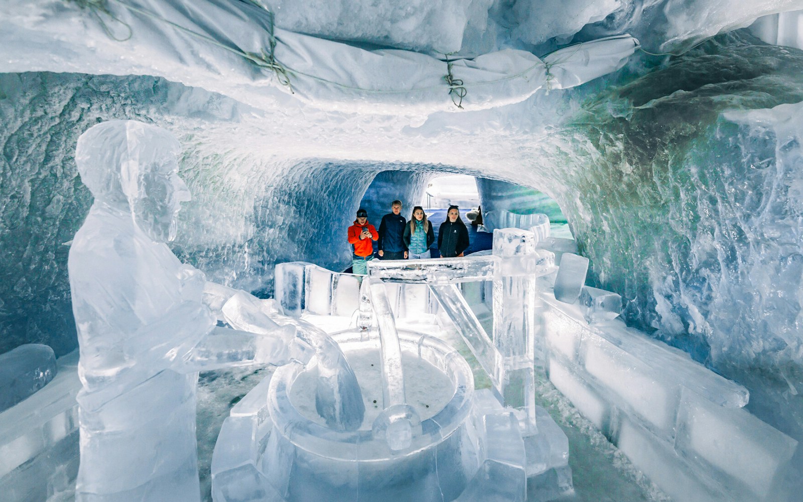 Visitors exploring ice sculptures in Glacier Paradise cave.