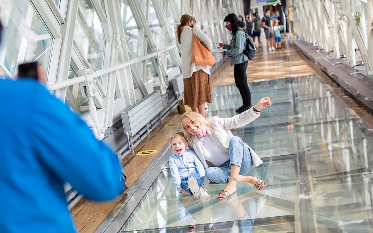 Visitors enjoying the glass walkway at Tower Bridge, London.