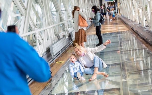 Visitors enjoying the glass walkway at Tower Bridge, London.