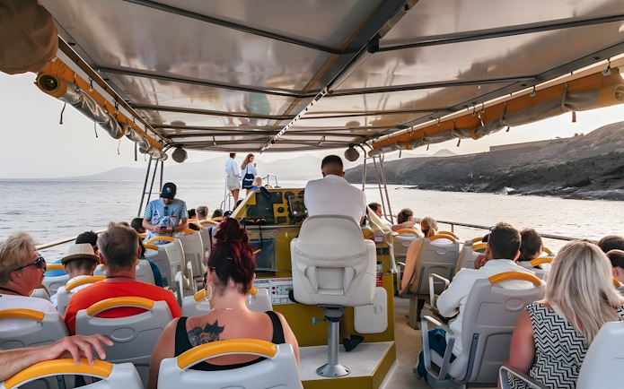 Tourists seated inside a speedboat during a sunset dolphin cruise near the coastline.