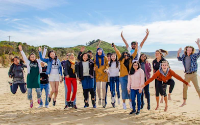 Group of people jumping on a beach during Bruny Island tour from Hobart.
