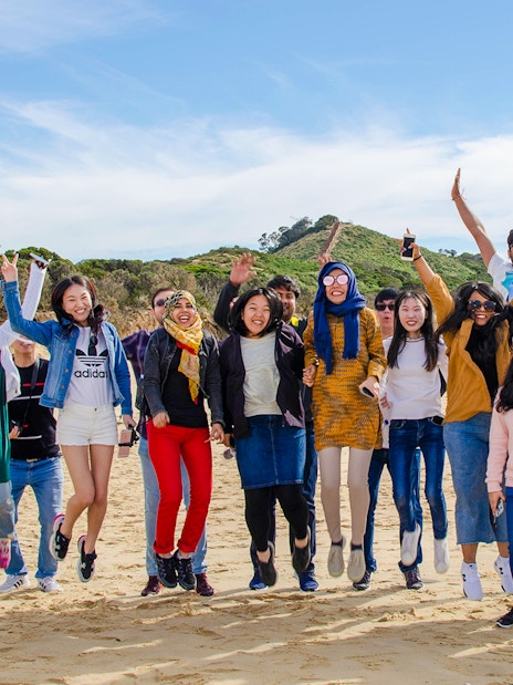 Group of people jumping on a beach during Bruny Island tour from Hobart.