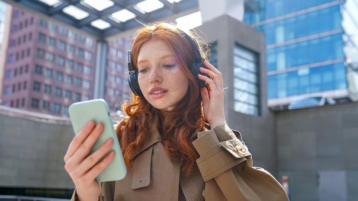 Person using headphones and smartphone for The Great Fire Monument audio guide.