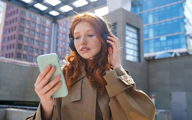 Person using headphones and smartphone for The Great Fire Monument audio guide.