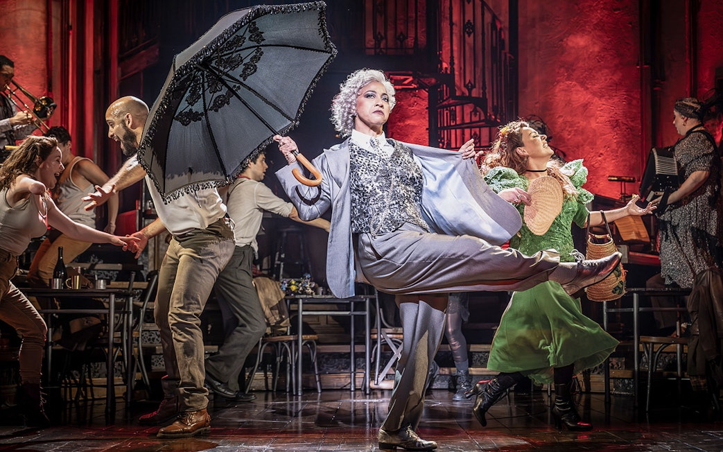 Performers dancing energetically on stage during a Hadestown musical scene.