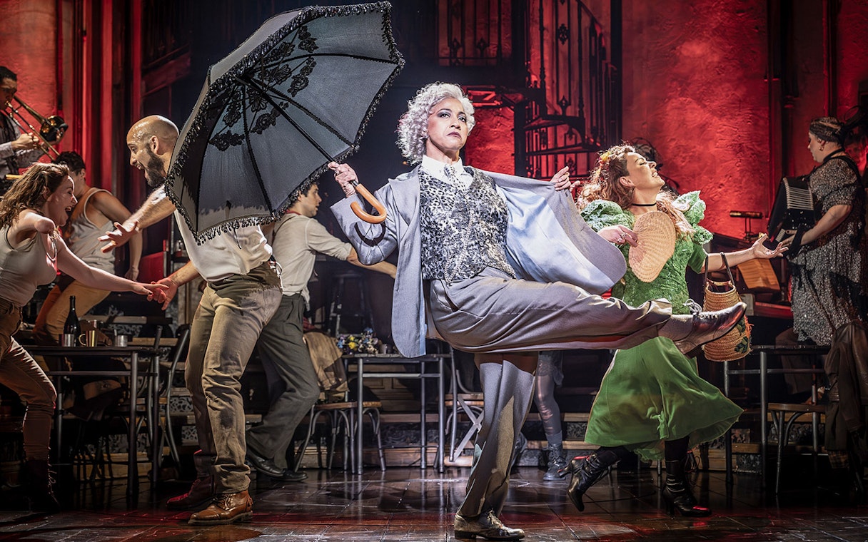 Performers dancing energetically on stage during a Hadestown musical scene.