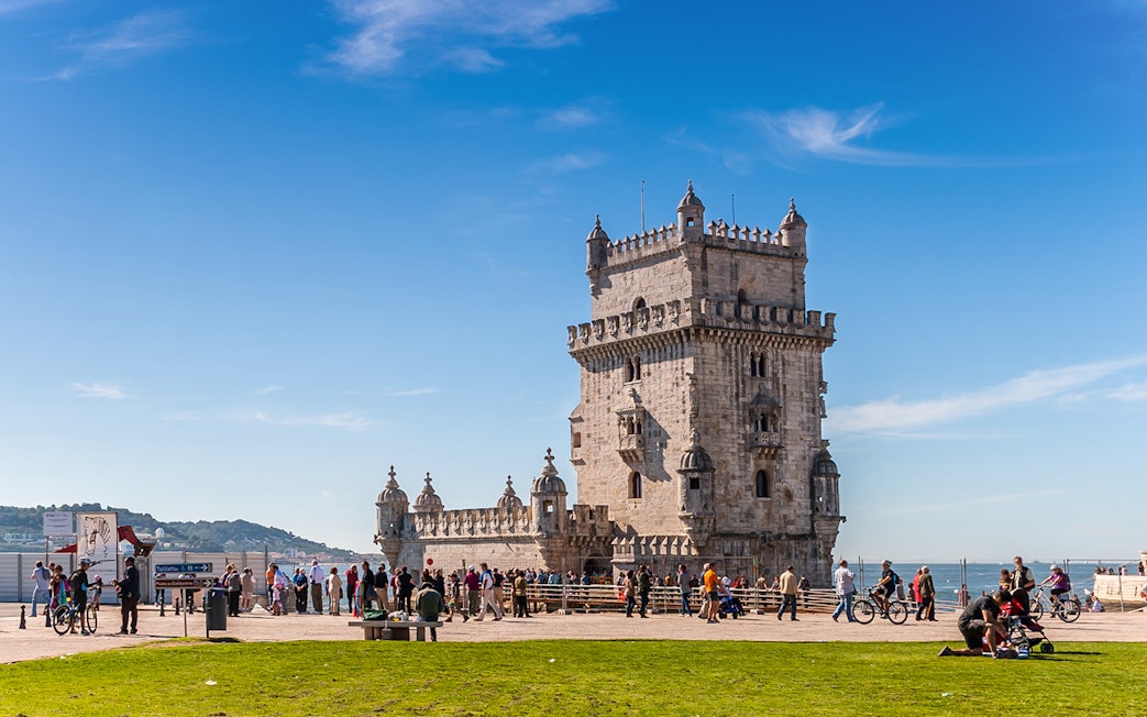 Belem Tower in Lisbon with tourists and cyclists nearby.