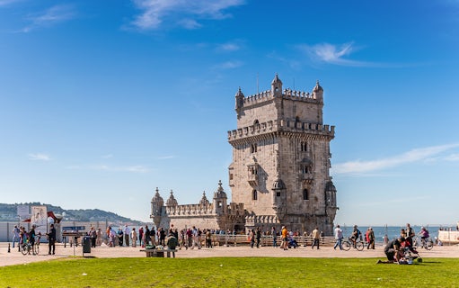 Belem Tower in Lisbon with tourists and cyclists nearby.