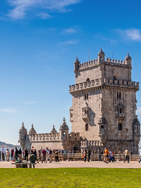 Belem Tower in Lisbon with tourists and cyclists nearby.