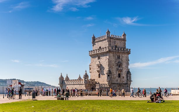 Belem Tower in Lisbon with tourists and cyclists nearby.