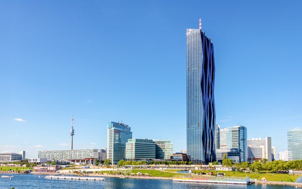 DC Tower I in Vienna, Austria, with surrounding modern buildings and river view.