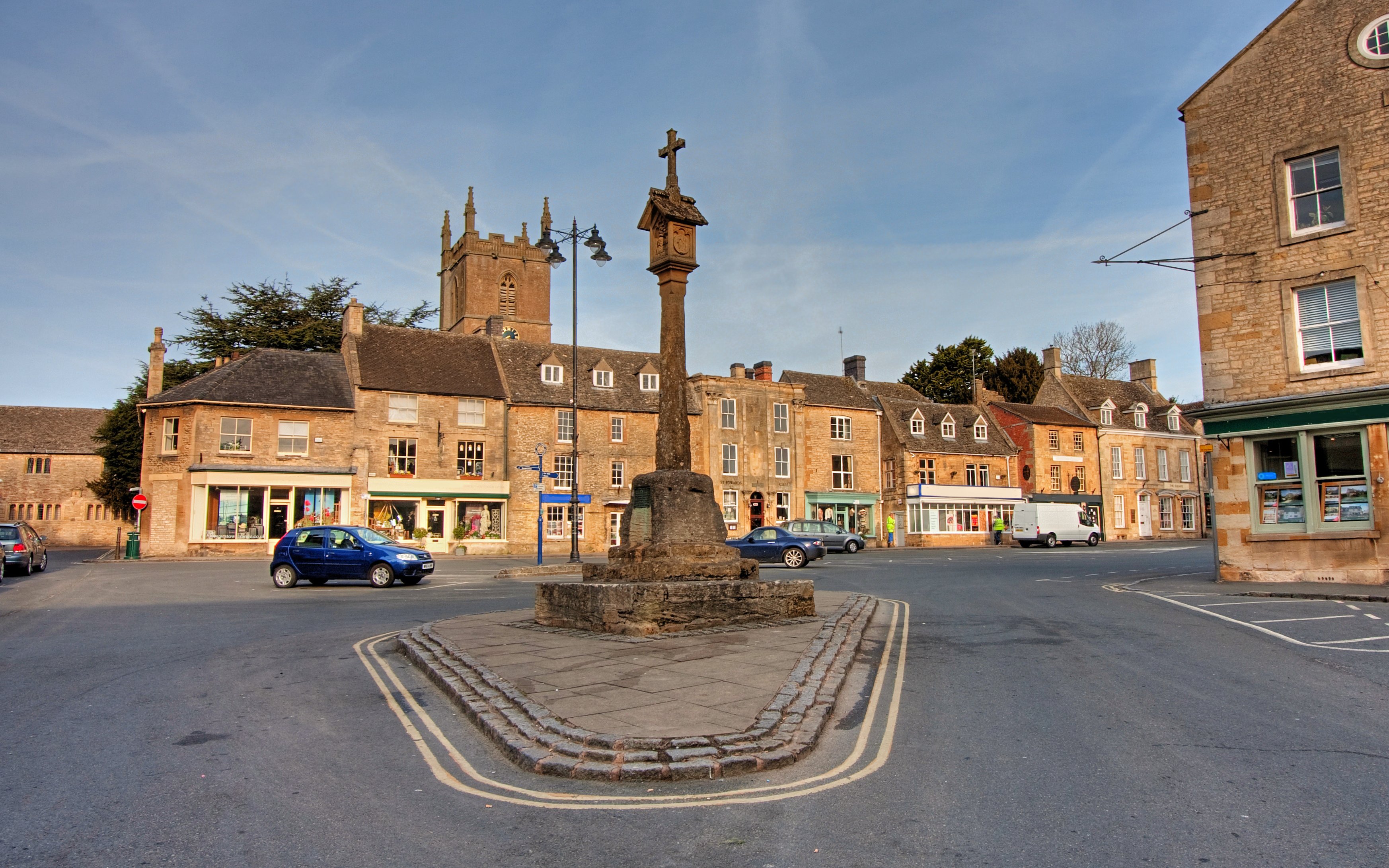 Market Square with historic buildings and a stone cross in Stow-on-the-Wold, England.