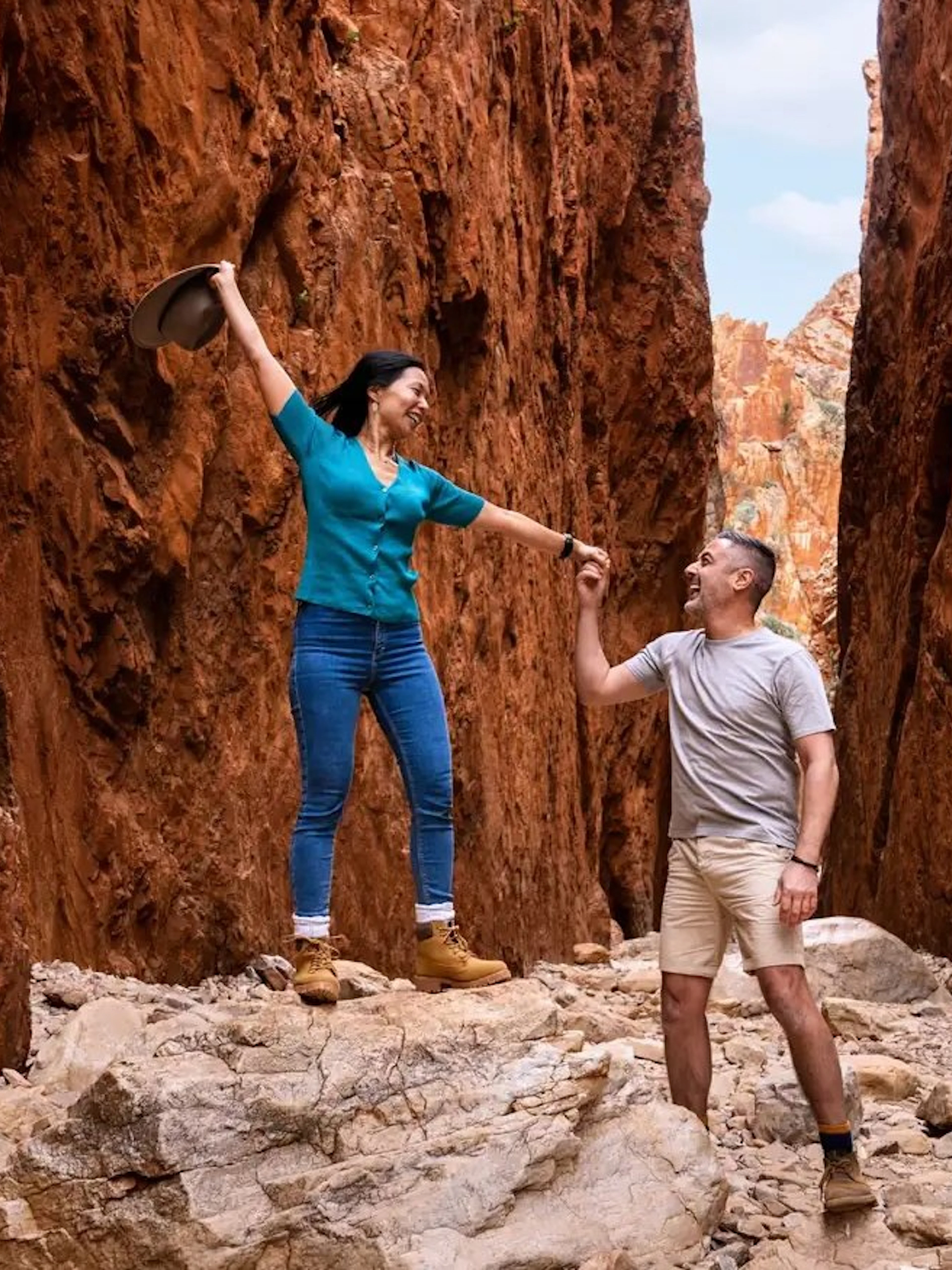 Couple exploring narrow red rock gorge on Uluru–Kata Tjuta camping tour.