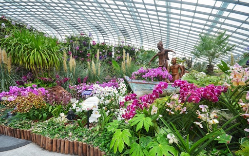 Flower Dome at Gardens by the Bay with vibrant orchids and wooden sculptures.