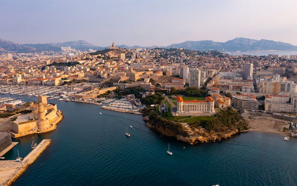 Aerial view of Marseille's sea district with historic forts and cityscape.