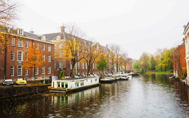 Amsterdam canal with houseboats and historic buildings on a SmallGroup Hidden Gems Tour.