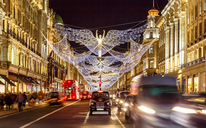 London street with Christmas lights and black cab during holiday season tour.