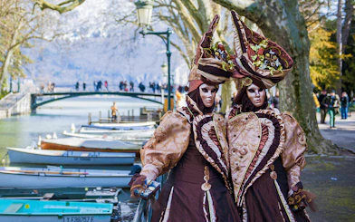 Carnival costumes by Lake Annecy with bridge and boats in the background, Geneva tour.