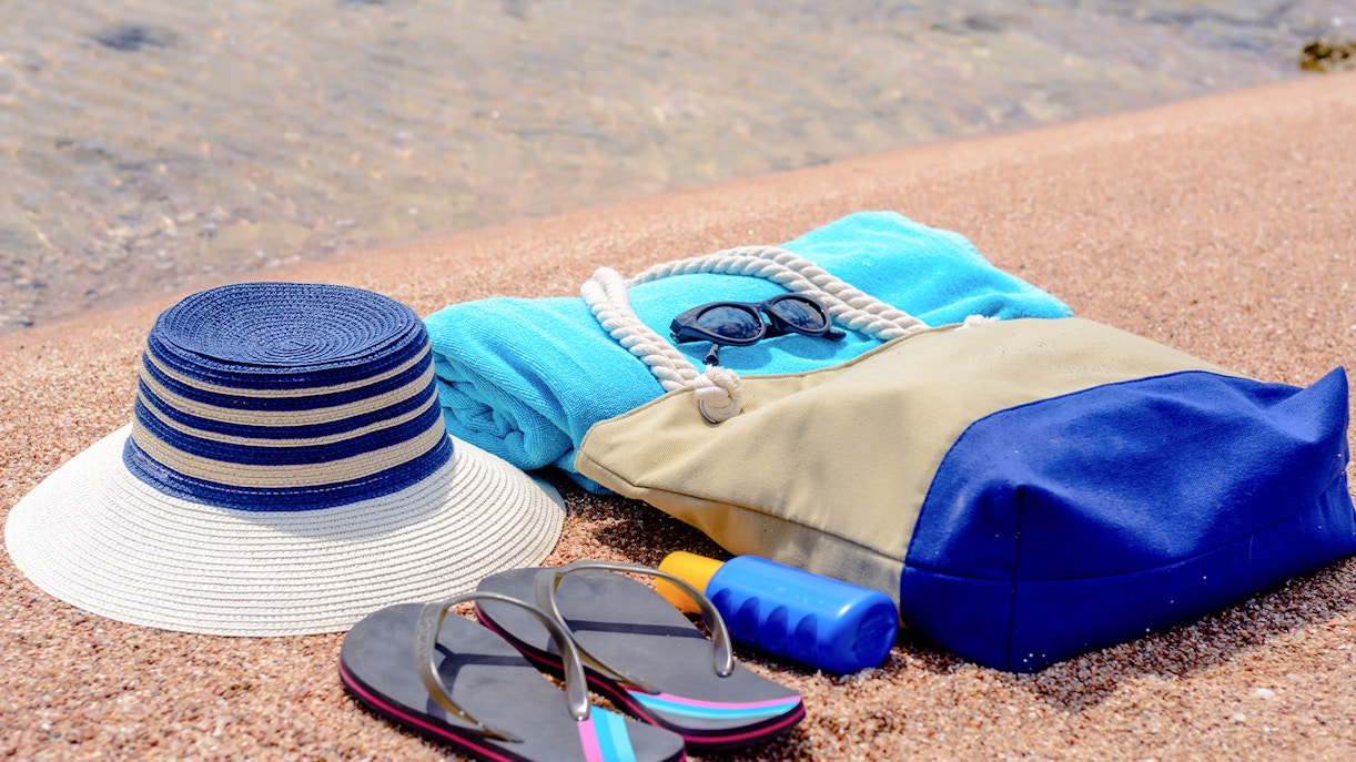 Beach essentials for snorkeling including a hat, towel, sunglasses, flip-flops, and sunscreen.