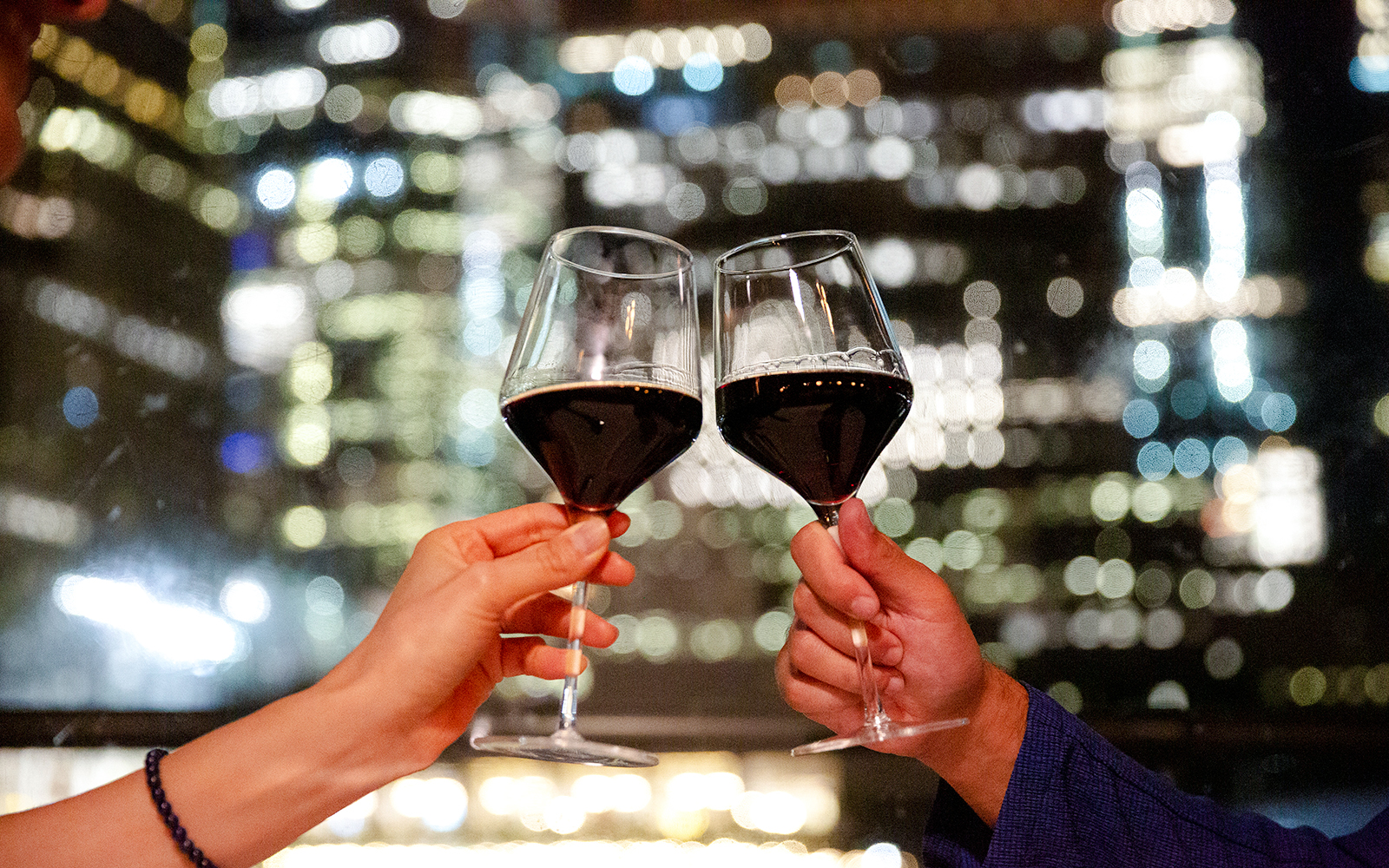 Toasting wine glasses against New Jersey cityscape on a signature cruise.