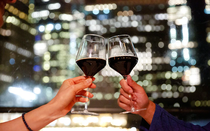 Toasting wine glasses against New Jersey cityscape on a signature cruise.